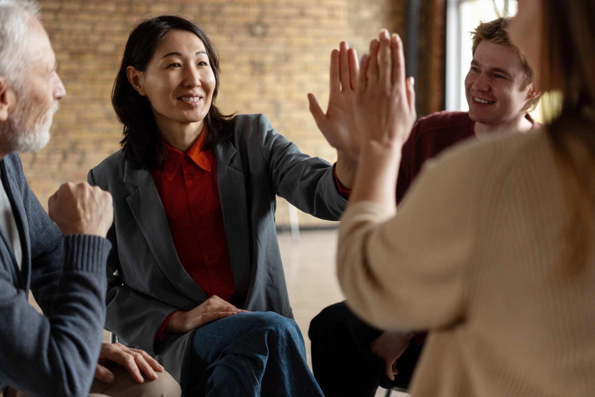 Diverse group participating in group counselling with high-five and smiles