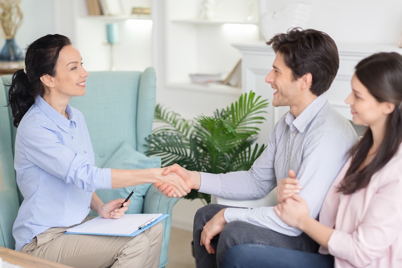 Professional psychologist and relieved couple handshaking after therapy